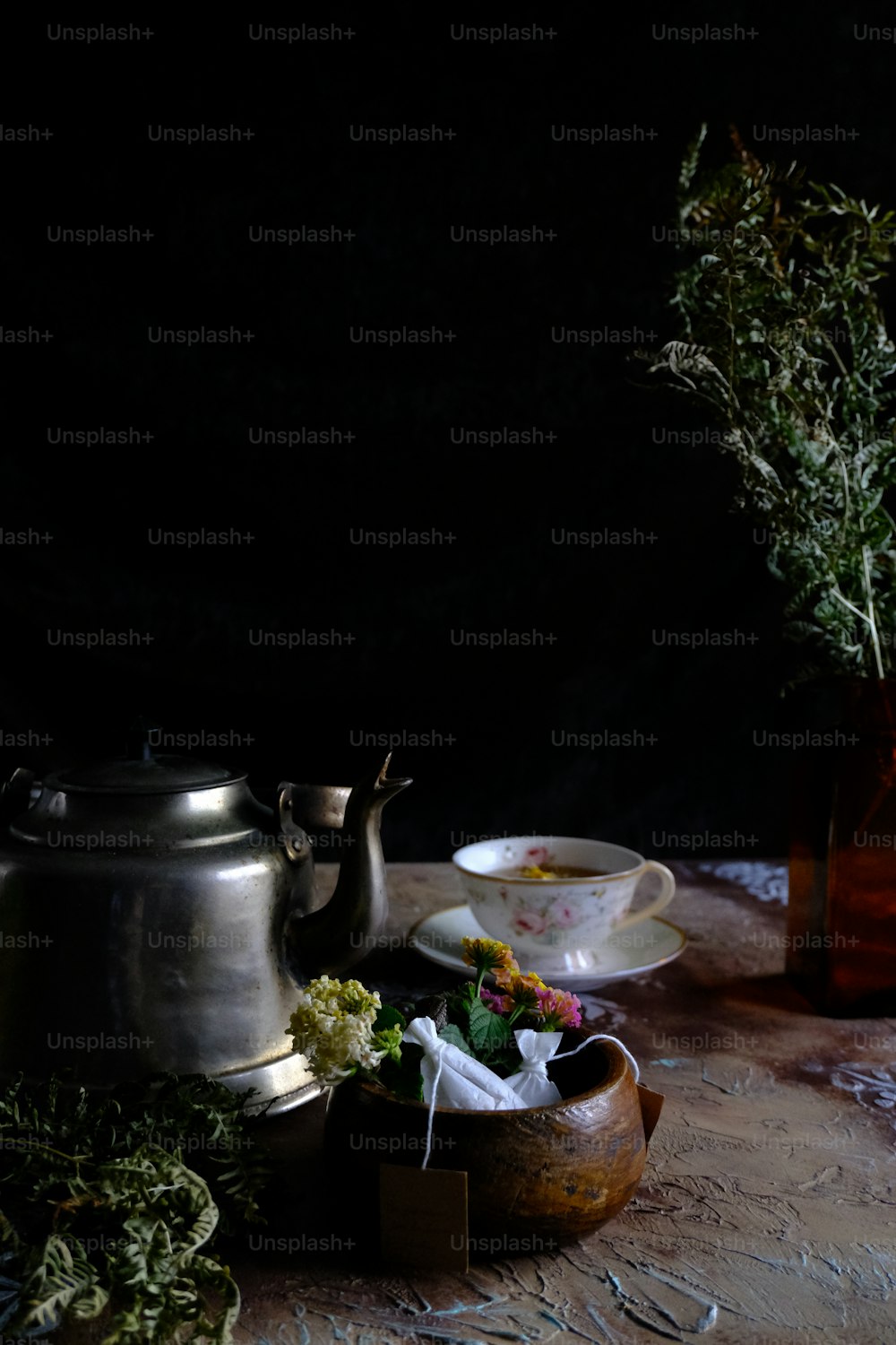 uma mesa coberta com um bule de chá ao lado de um vaso cheio de flores