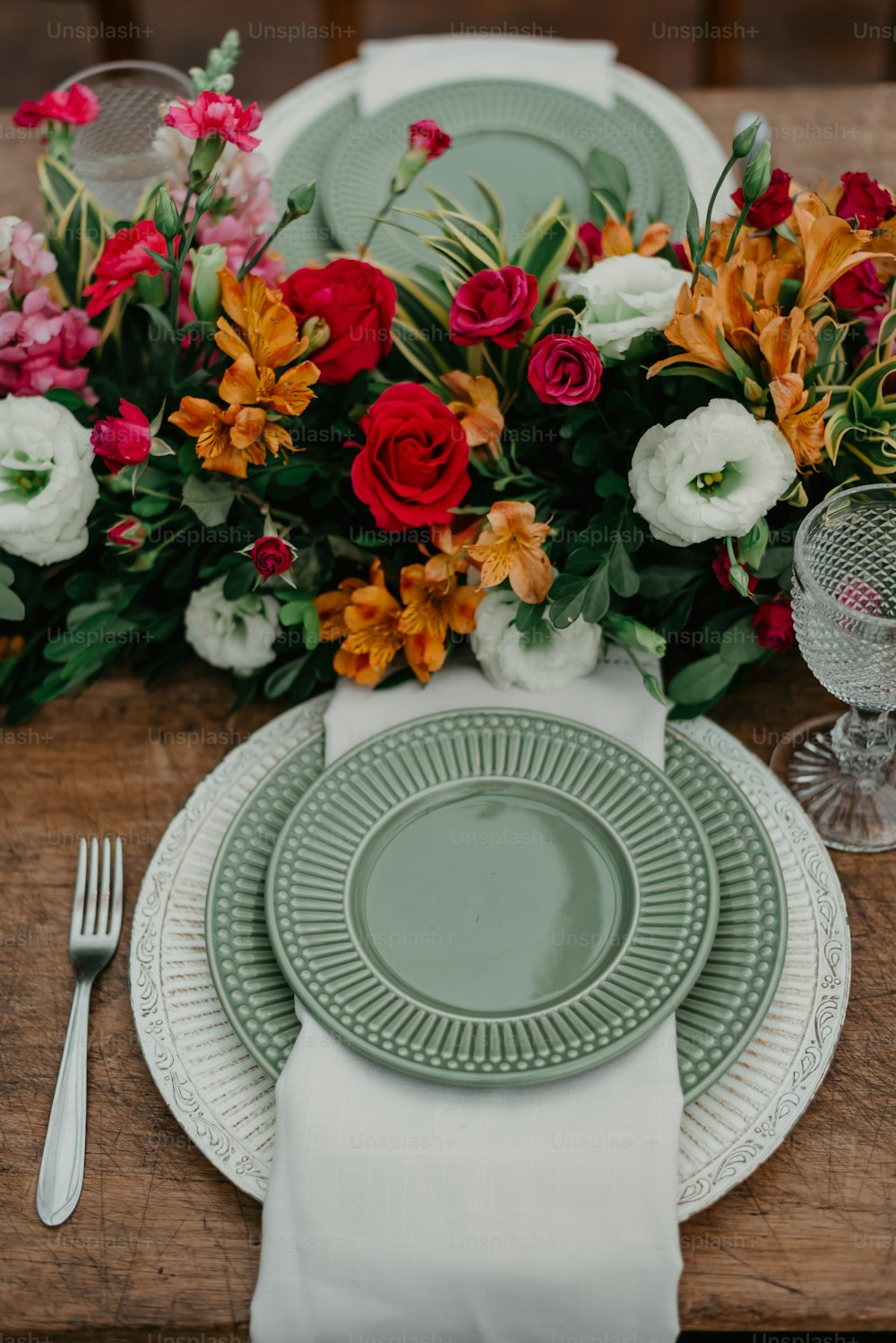 uma mesa de madeira coberta com pratos e flores