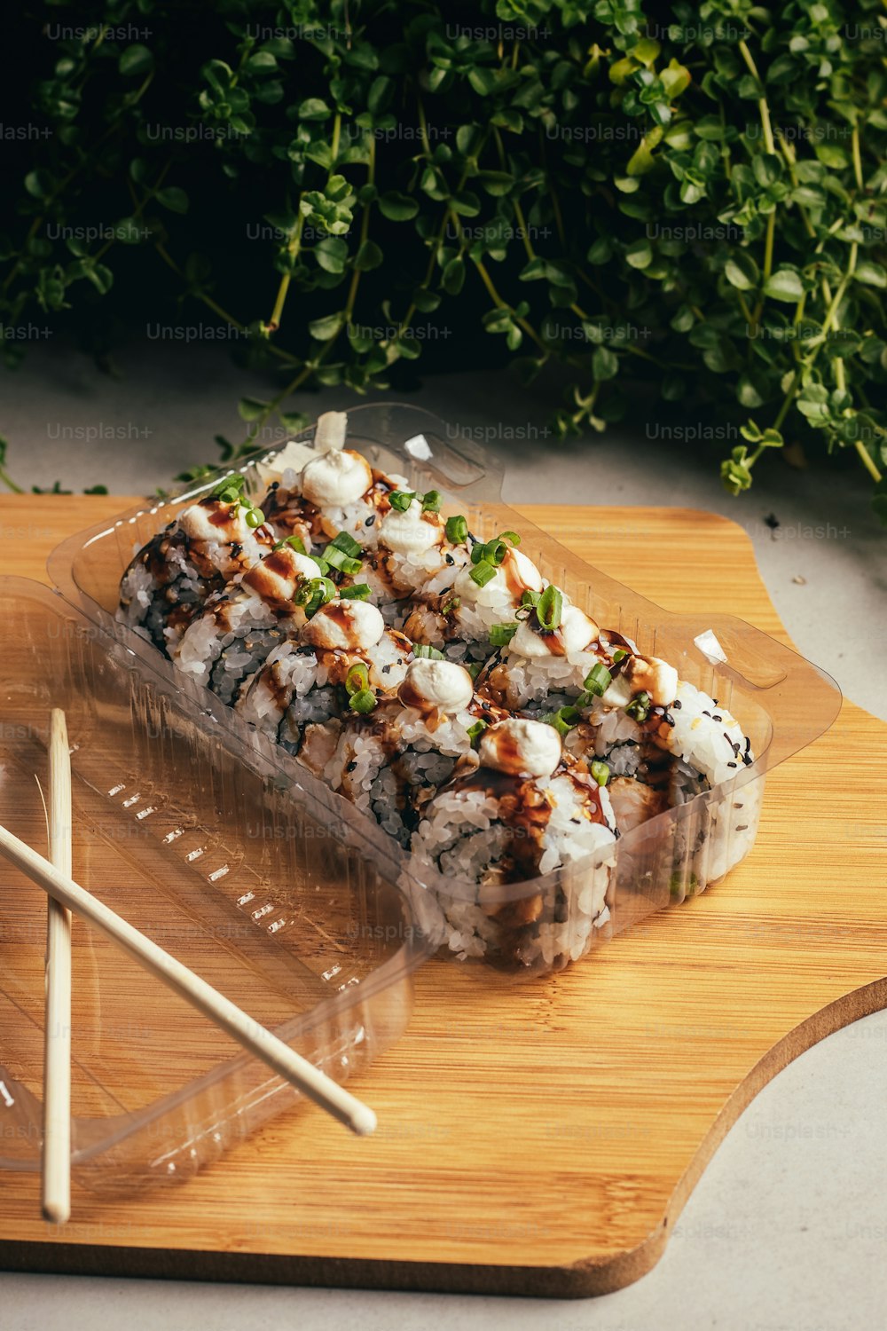 uma tábua de corte de madeira coberta com sushi e pauzinhos