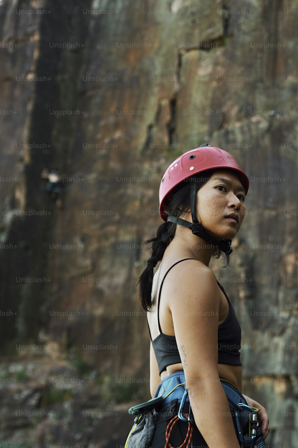a woman wearing a helmet standing in front of a rock face