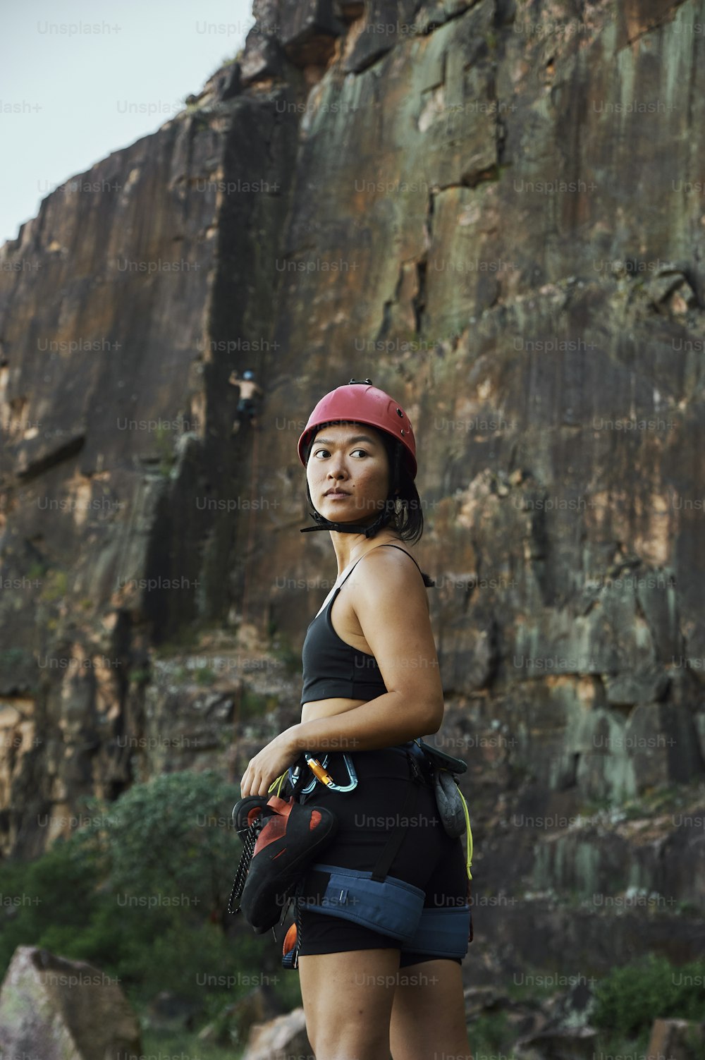 a woman wearing a helmet standing in front of a mountain