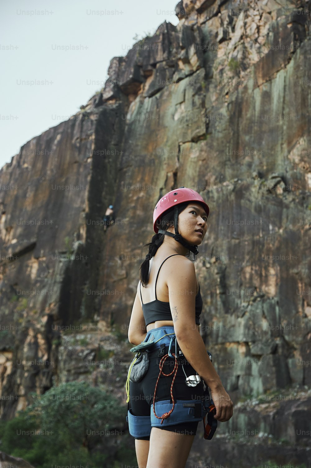 uma mulher que usa um capacete em pé na frente de uma montanha