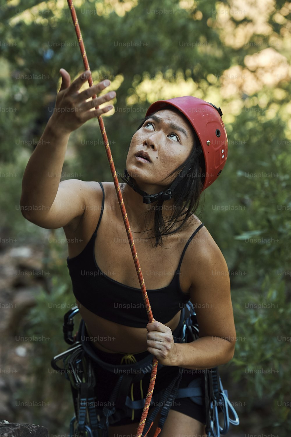 uma mulher em um capacete vermelho está escalando