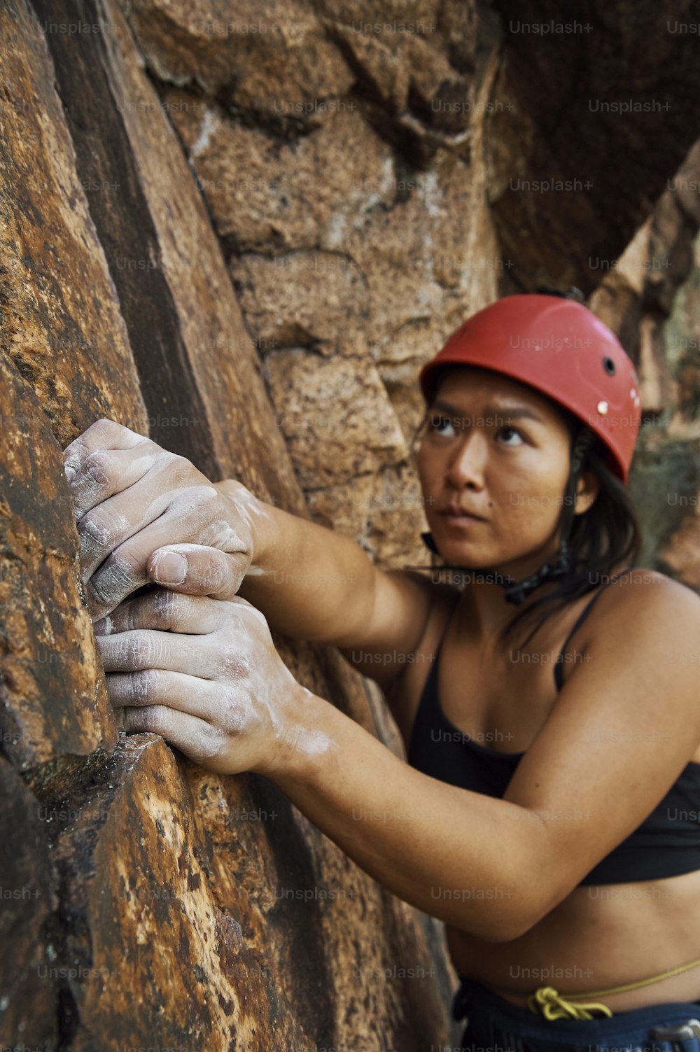 a woman climbing up a rock wall with a helmet on