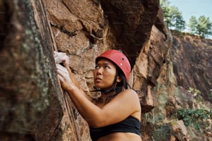 a woman in a red helmet climbing up a rock