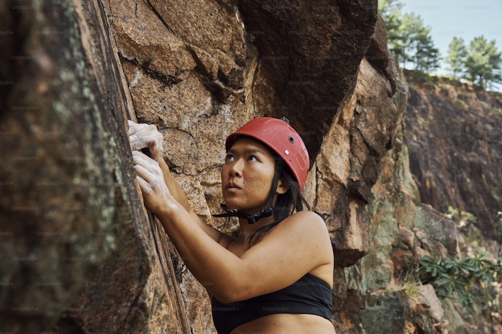 a woman in a red helmet climbing up a rock