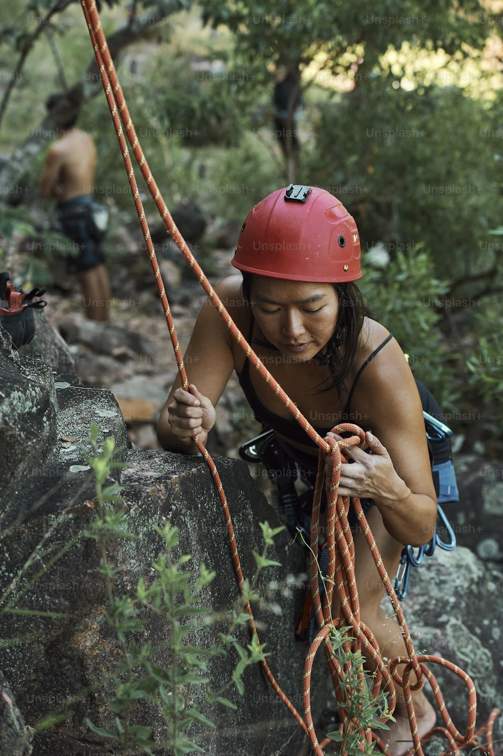 a woman climbing up a rock with a red helmet