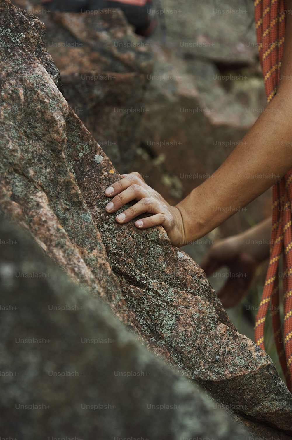 a person climbing up a rock with their hand on the rock