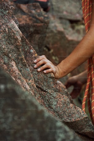 a person climbing up a rock with their hand on the rock