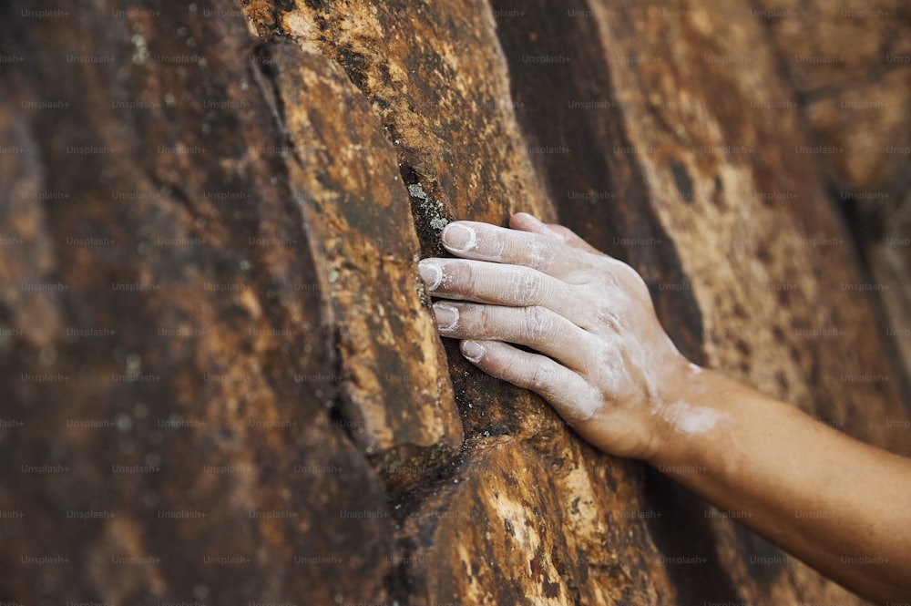 a person's hand on the side of a rock