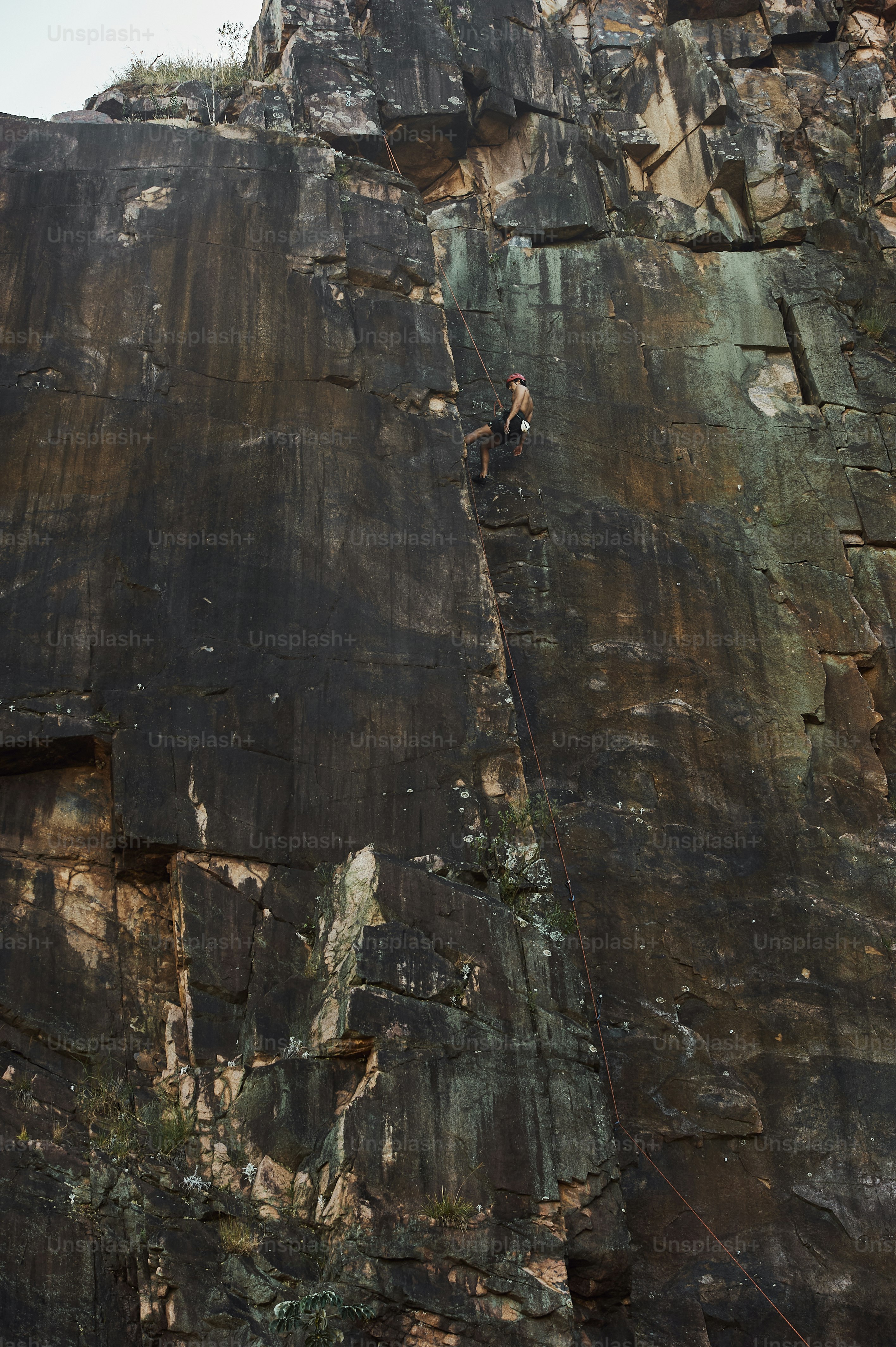 Un homme grimpant sur le flanc d’une montagne