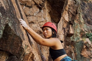 Eine Frau trägt einen Helm und klettert auf einen Felsen