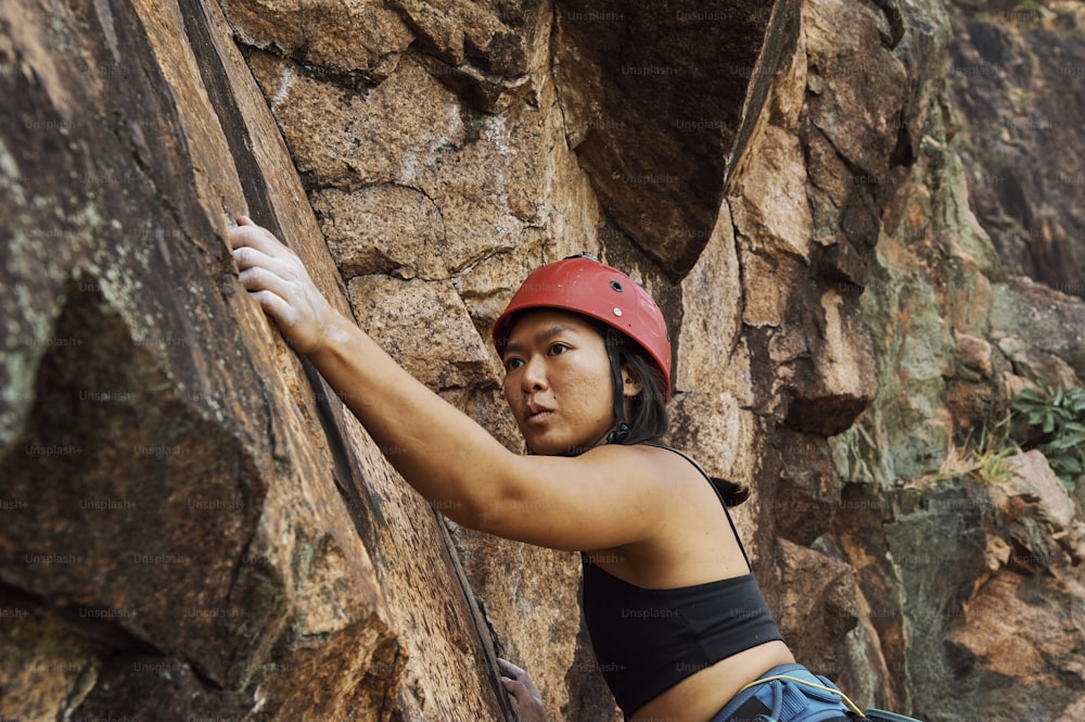uma mulher usando um capacete e escalando em uma rocha
