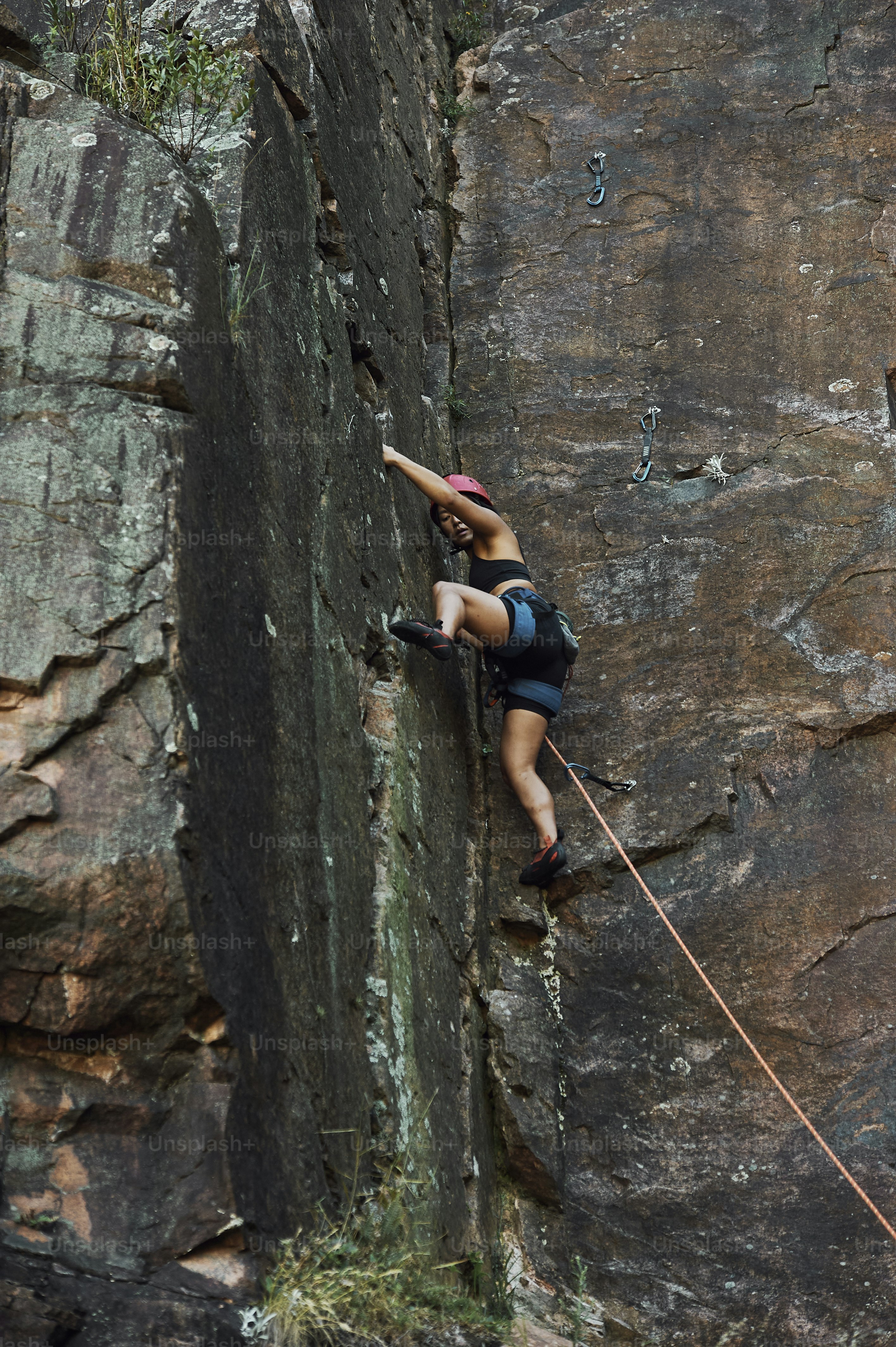 a woman climbing up the side of a cliff