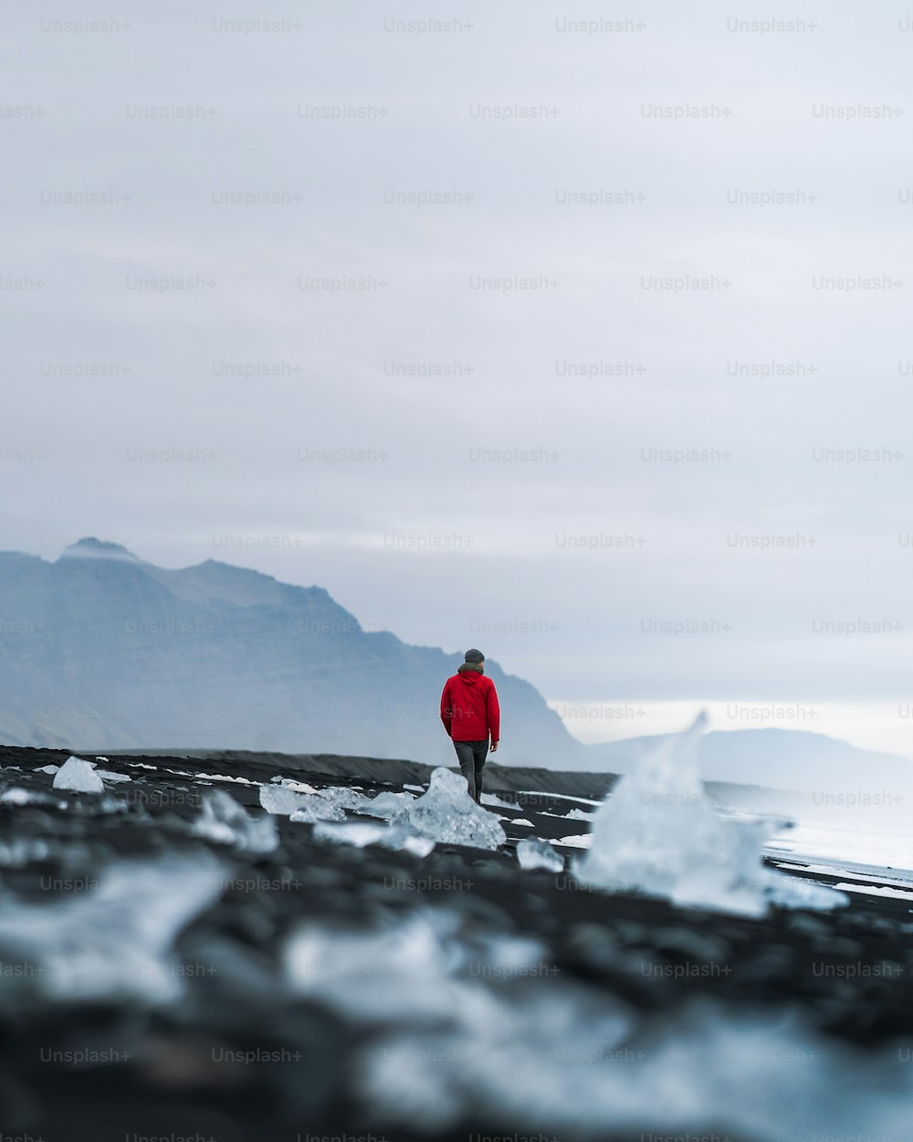Un uomo con una giacca rossa è in piedi sul ghiaccio