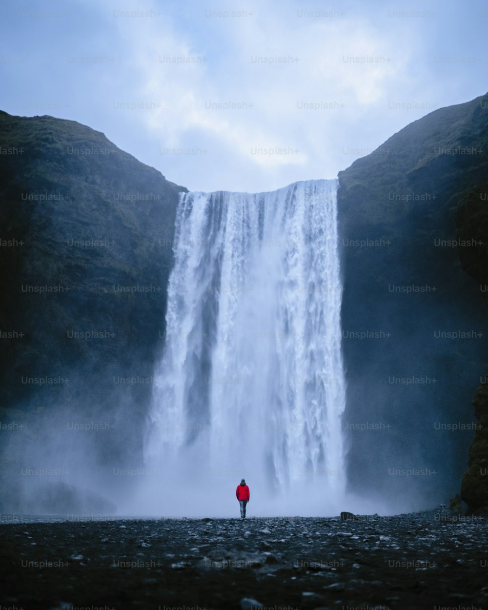 une personne debout devant une cascade
