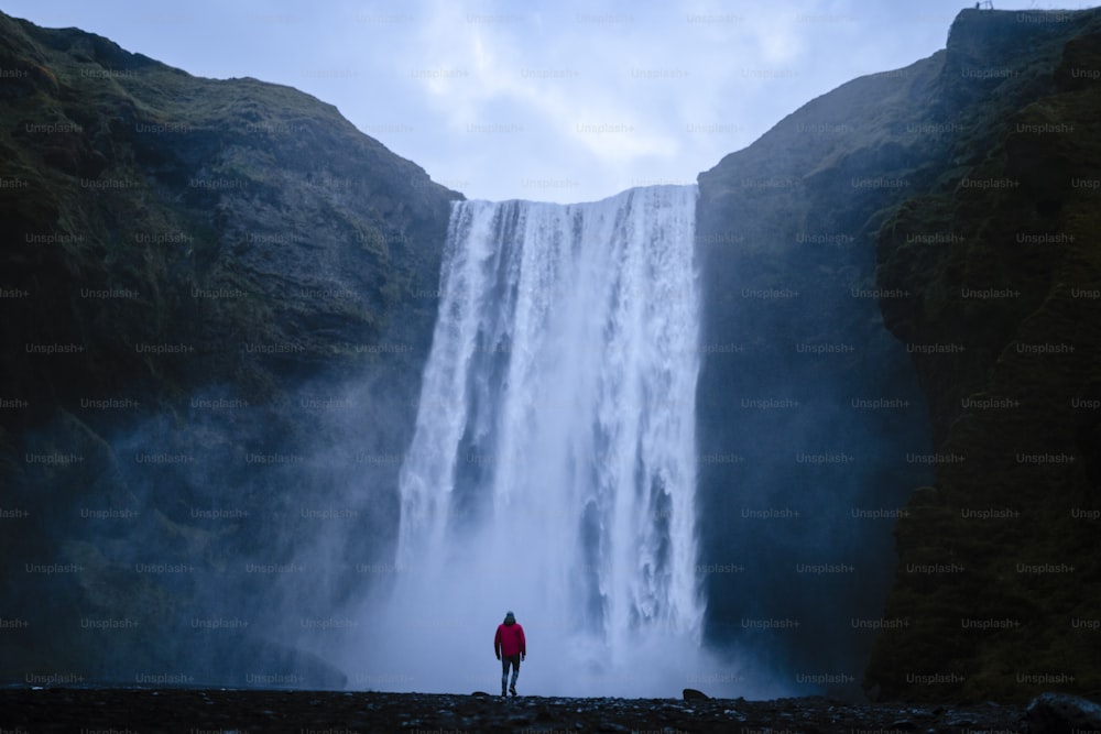 une personne debout devant une cascade