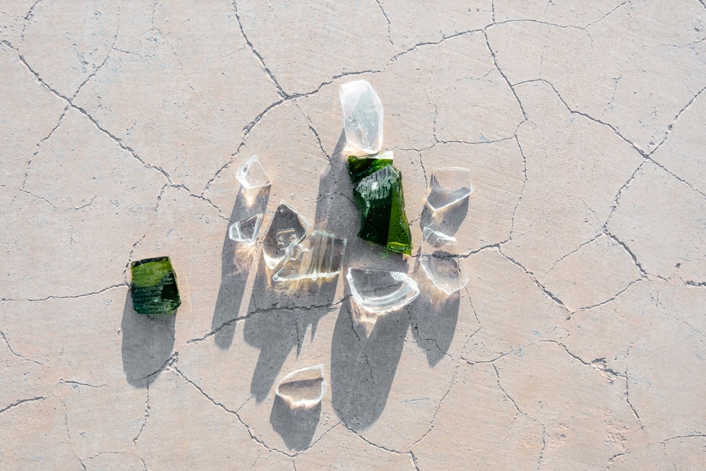 a couple of green bottles sitting on top of a cracked surface