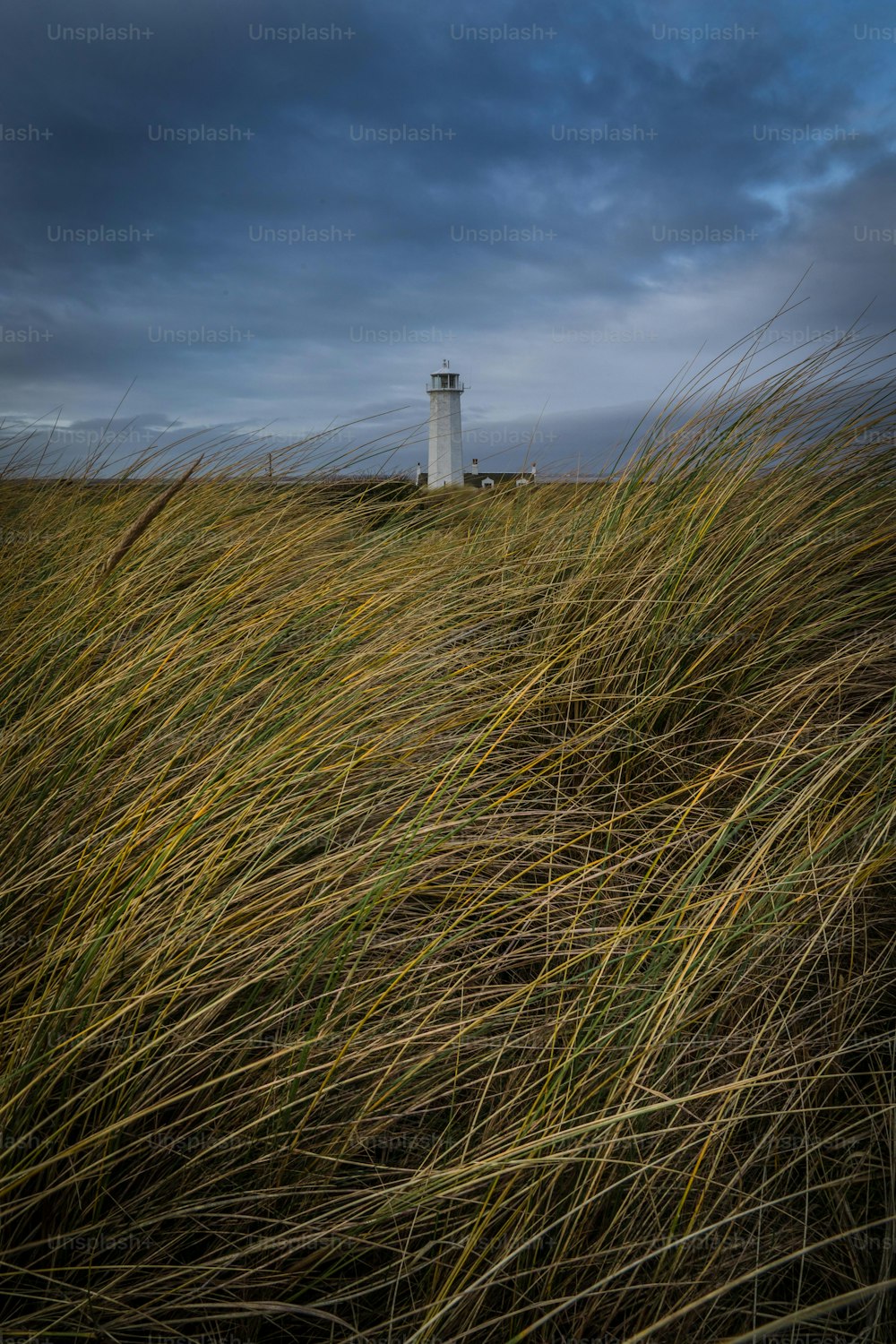 Un faro su una collina erbosa sotto un cielo nuvoloso