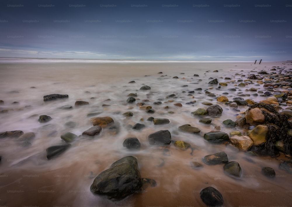 a long exposure photo of rocks on the beach