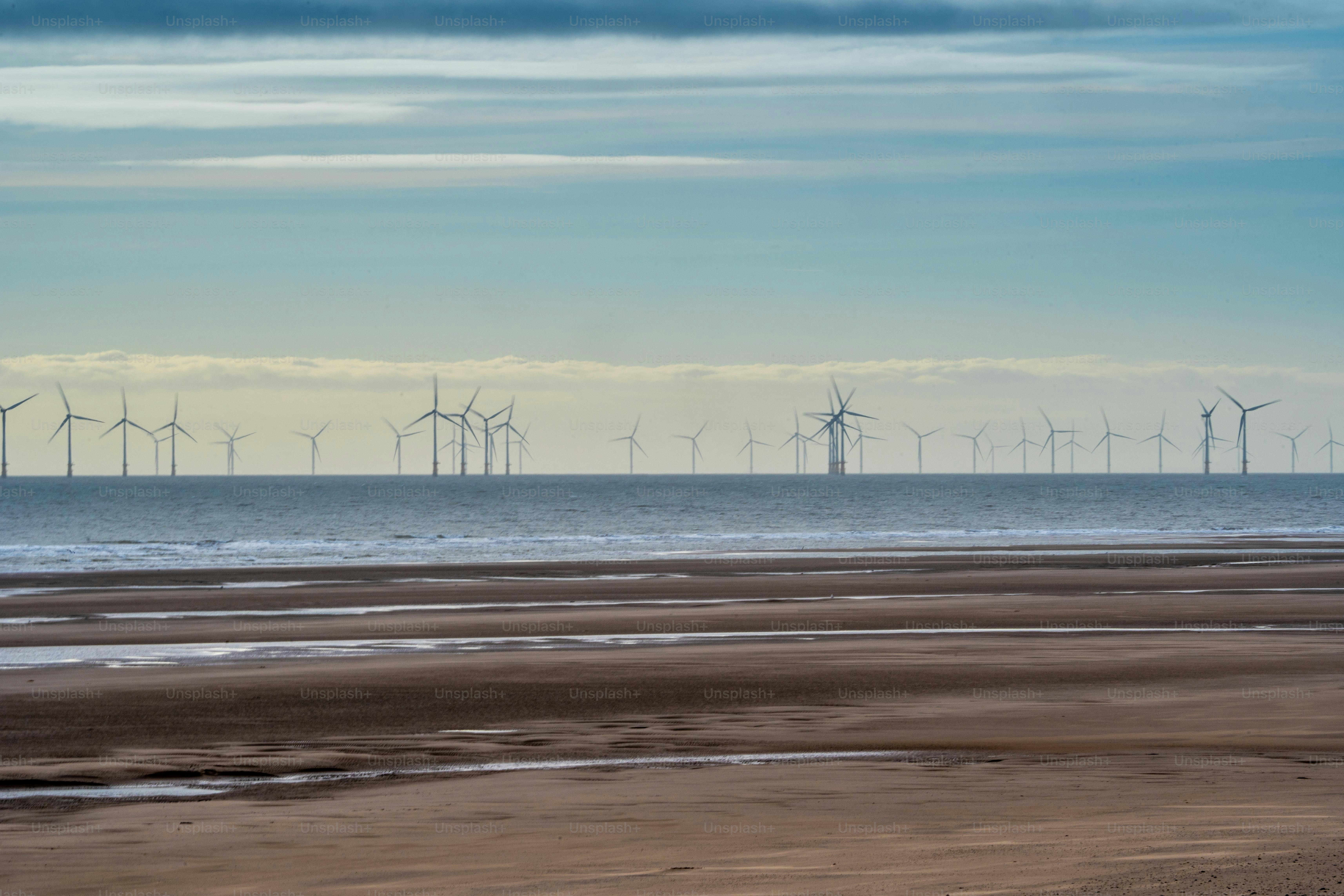 a group of windmills in the distance on a beach