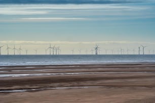 a group of windmills in the distance on a beach