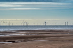 a group of windmills in the distance on a beach