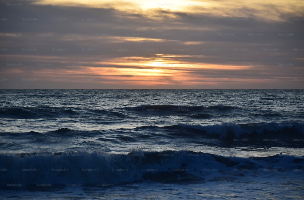 o sol está se pondo sobre as ondas do oceano