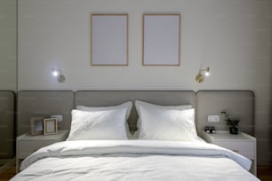 una cama blanca con dos cuadros enmarcados encima