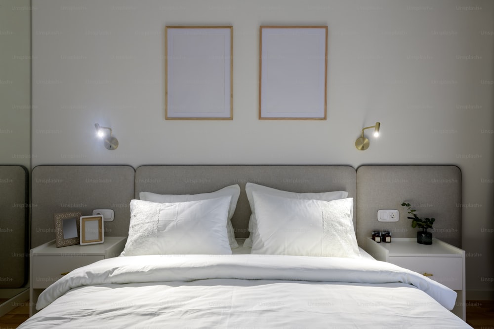 una cama blanca con dos cuadros enmarcados encima