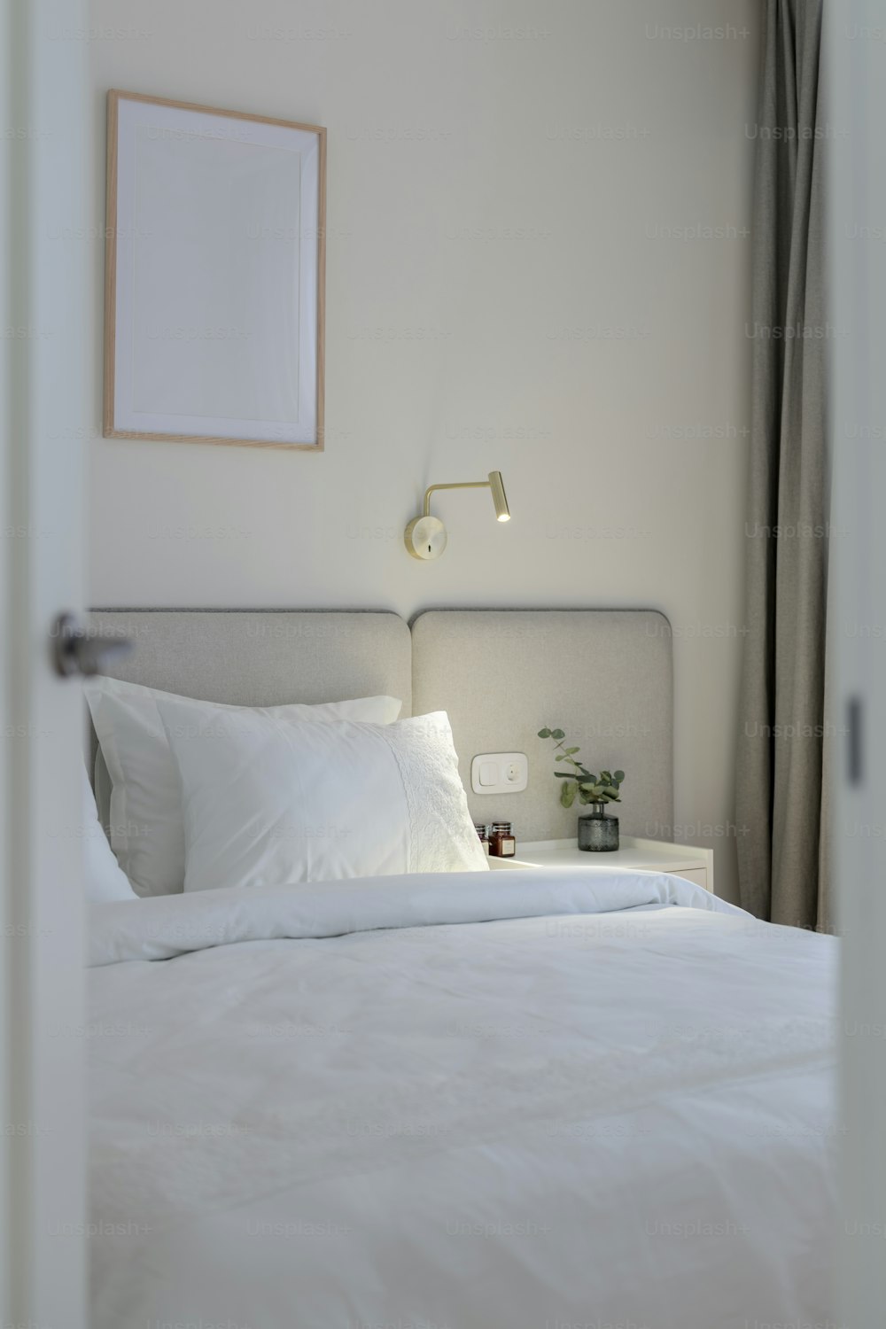 un letto bianco con lenzuola e cuscini bianchi