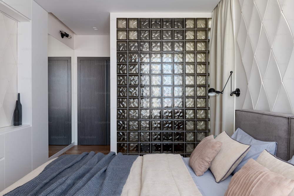 a bedroom with a bed and a glass block wall