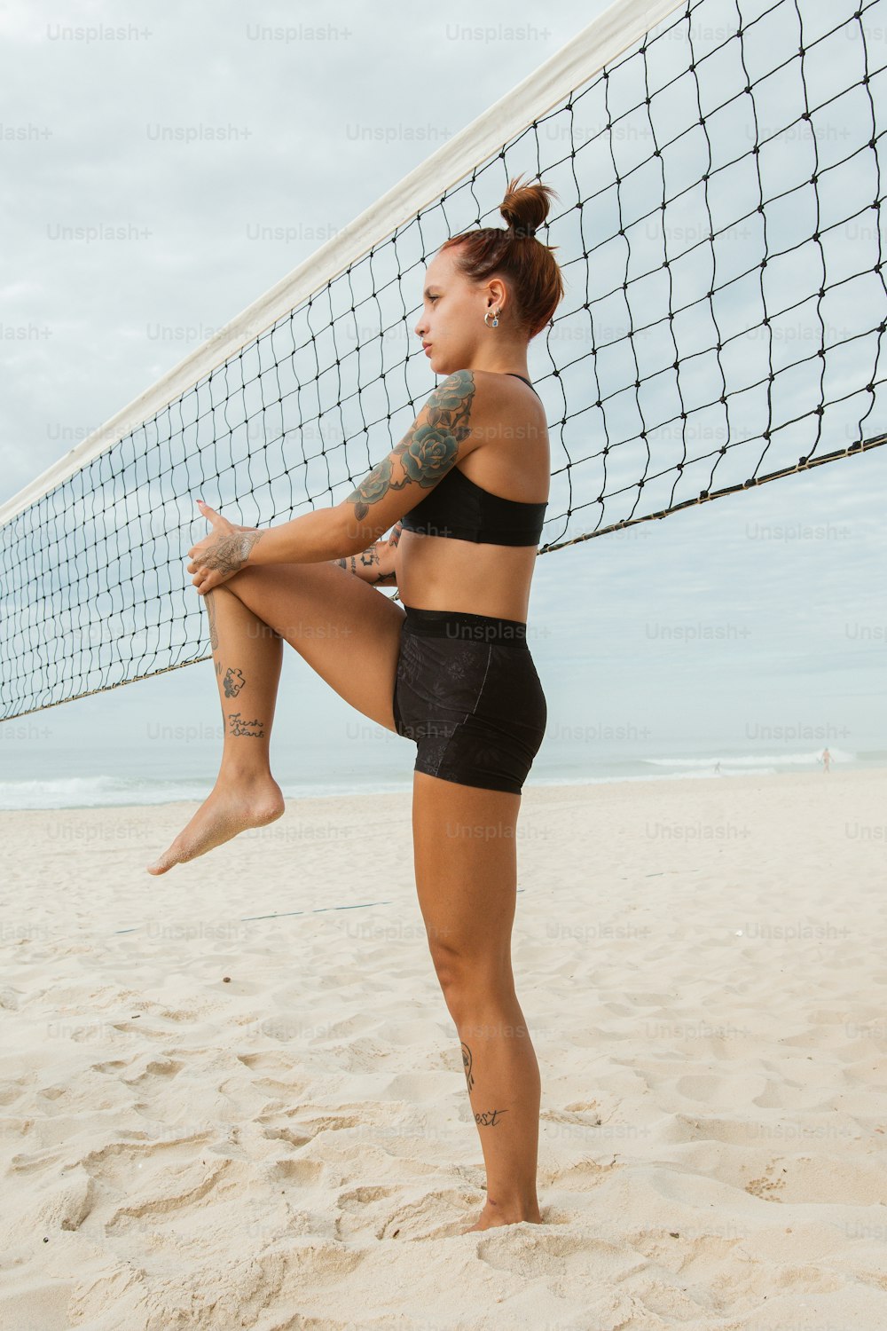 uma mulher em pé em uma praia ao lado de uma rede de voleibol