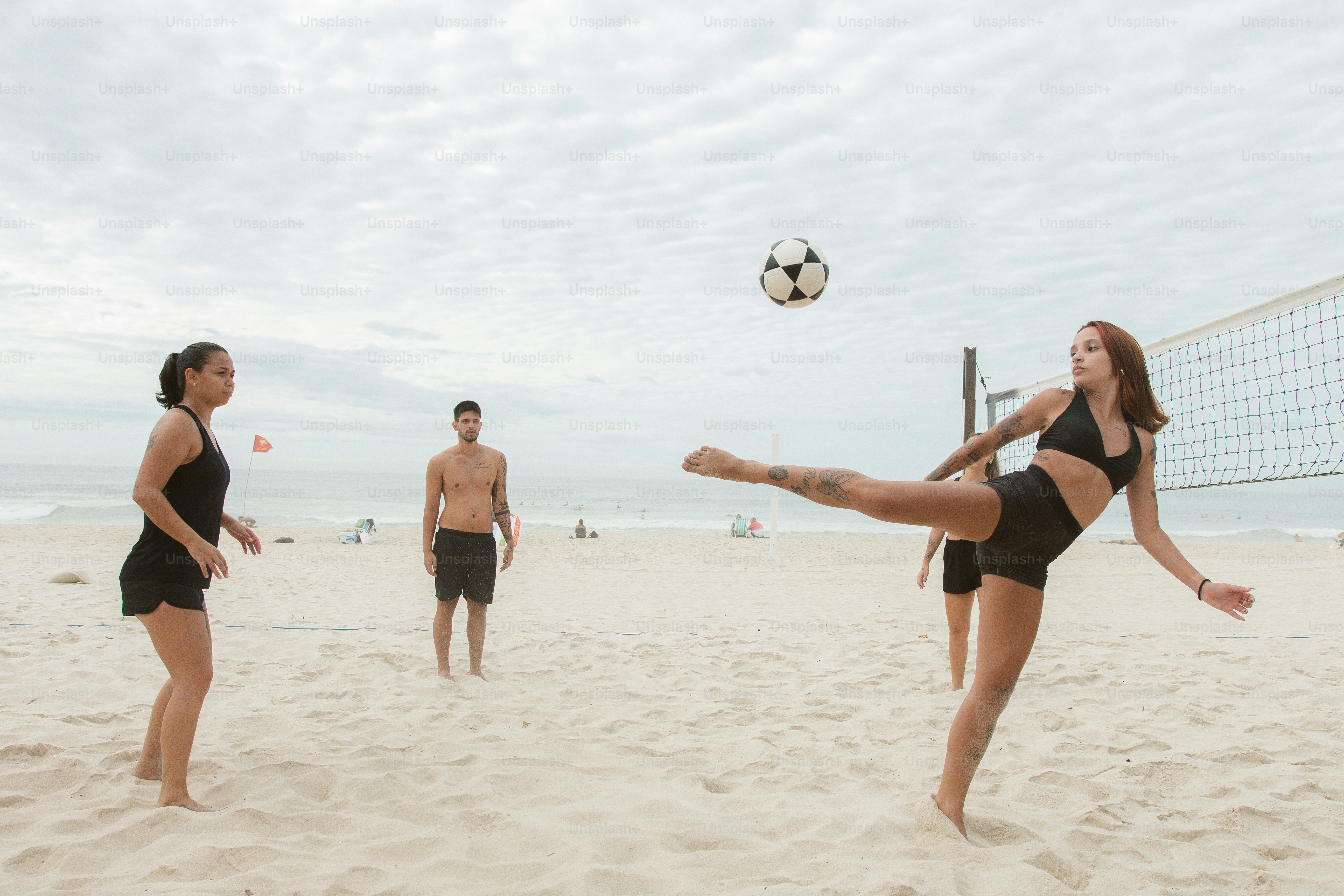 A woman kicking a volleyball ball across a beach photo Volleyball