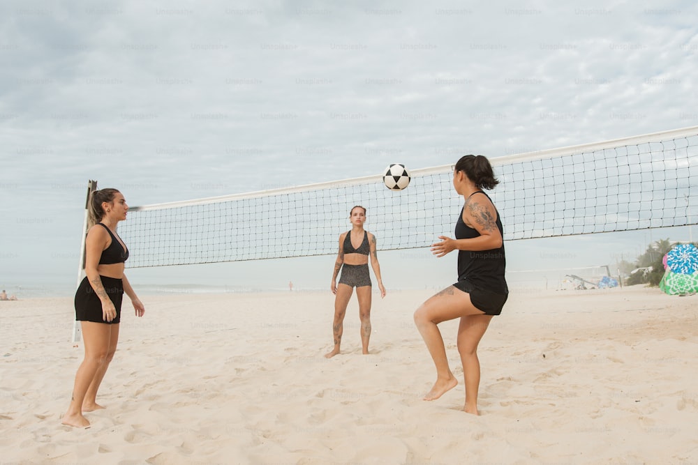 a group of women playing a game of volleyball on the beach