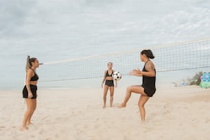a group of young women playing a game of volleyball on the beach