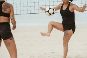 Una mujer pateando una pelota de voleibol en la playa