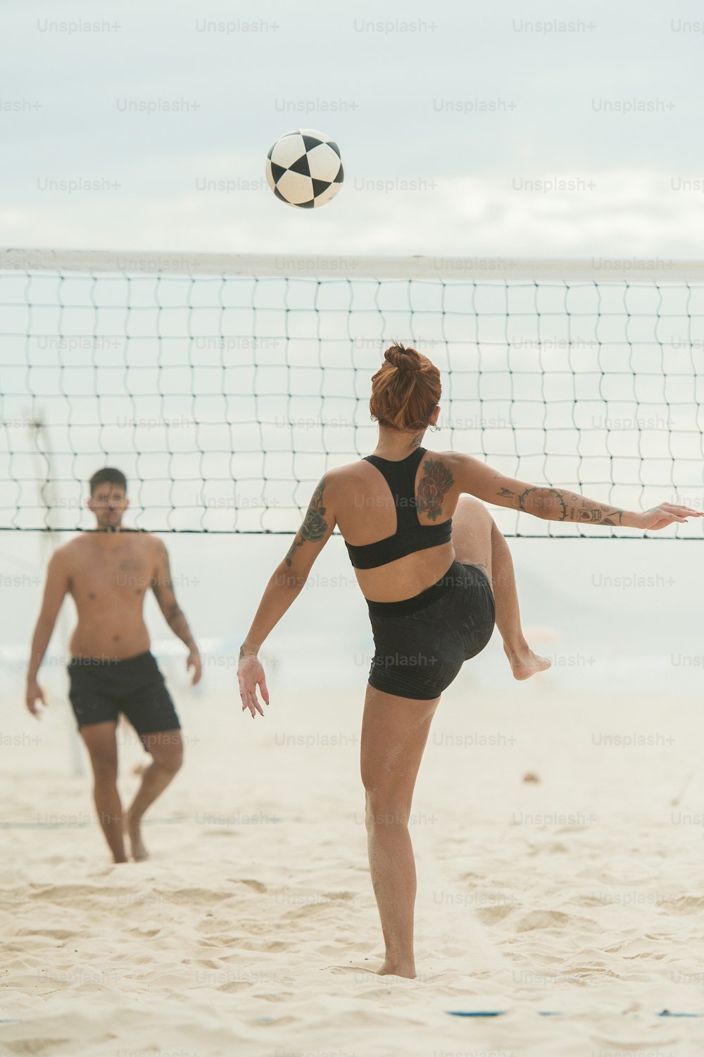 a woman in a black swimsuit hitting a volleyball