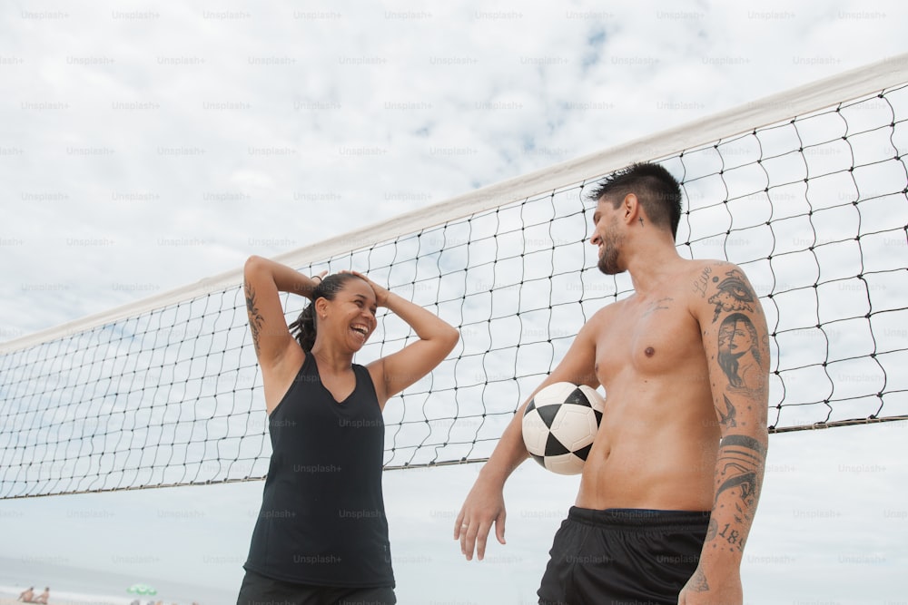 a man and a woman standing next to a volleyball net