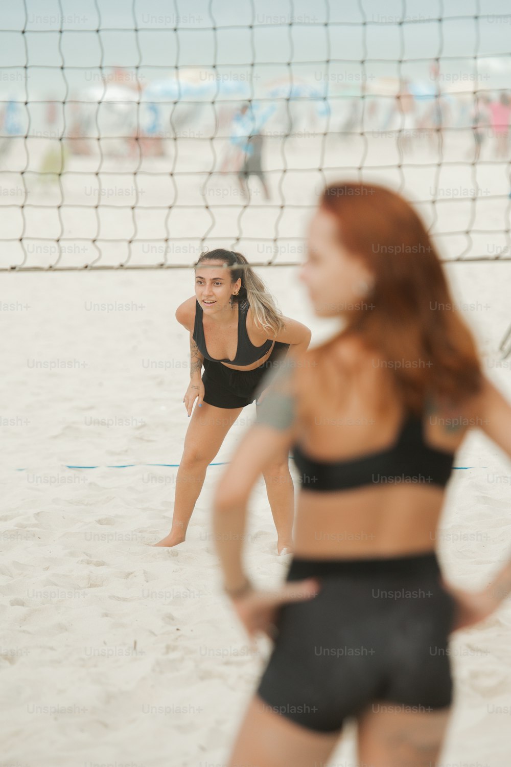 uma mulher em pé em uma praia ao lado de uma rede de voleibol