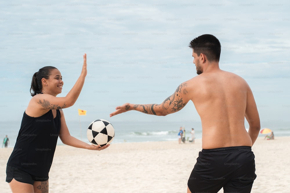 a man and a woman on the beach playing with a soccer ball