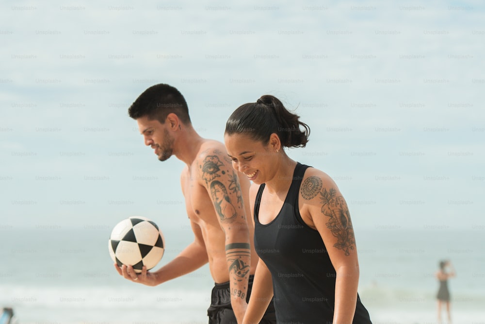 um homem e uma mulher jogando futebol na praia