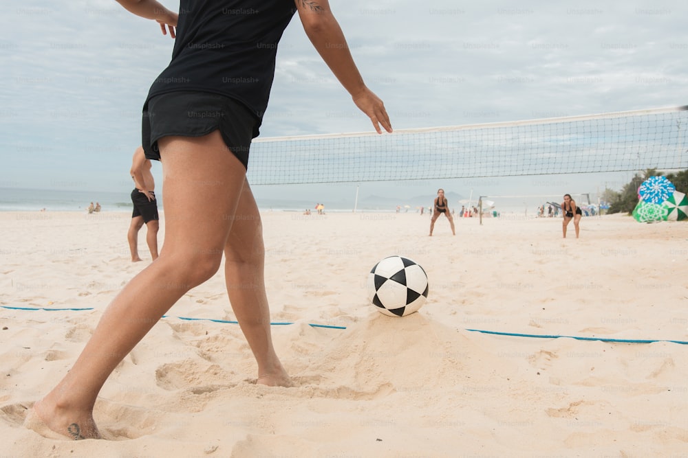 a woman kicking a soccer ball on a beach