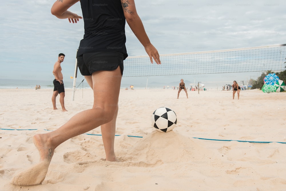 a person kicking a soccer ball on a beach
