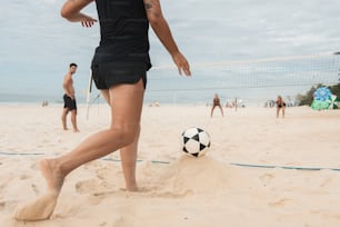 una persona pateando una pelota de fútbol en una playa