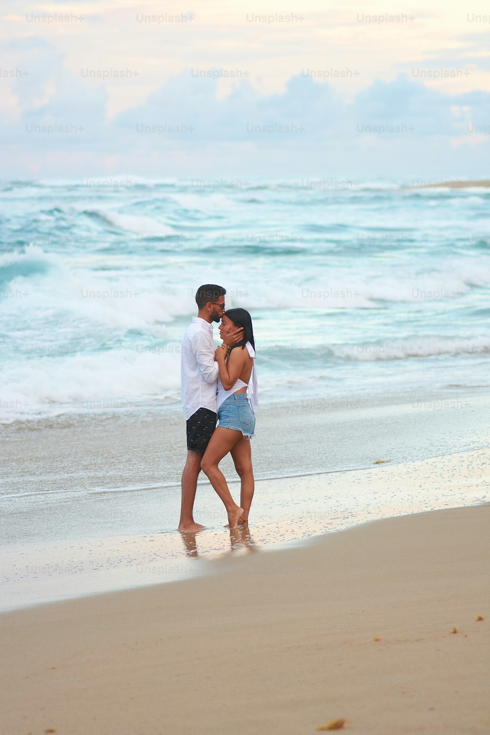 Un hombre y una mujer parados en una playa junto al océano