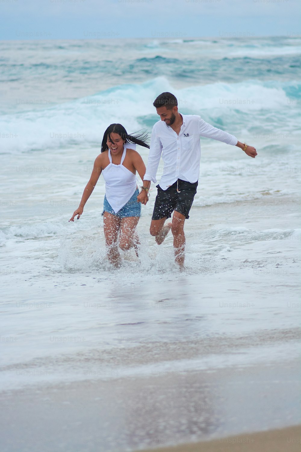 a man and a woman are walking in the ocean