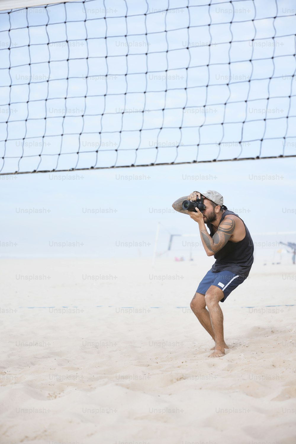 Un hombre parado en una playa junto a una red de voleibol