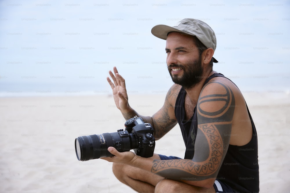 um homem sentado em uma praia segurando uma câmera