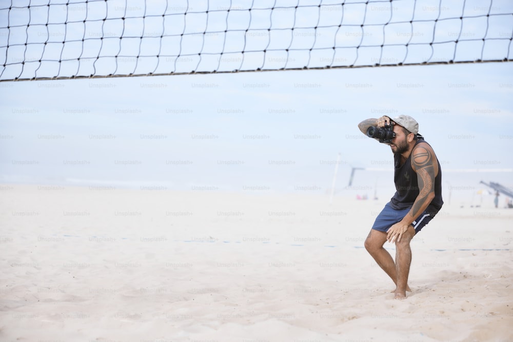 Ein Mann steht am Strand neben einem Volleyballnetz